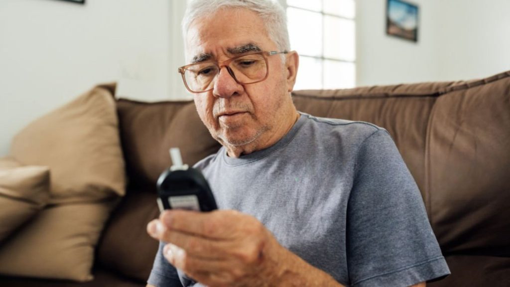 Older man checking blood sugar levels due to diabetes risk