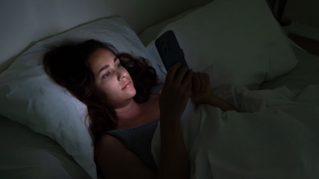 Woman using smartphone in bed causing digital sleep disruption